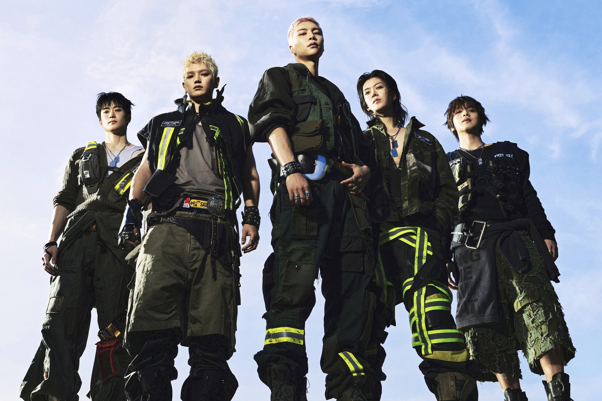 I cinque membri degli NCT 127 uno accanto all'altro davanti a un cielo aperto in una foto concept del settimo album BLINGY