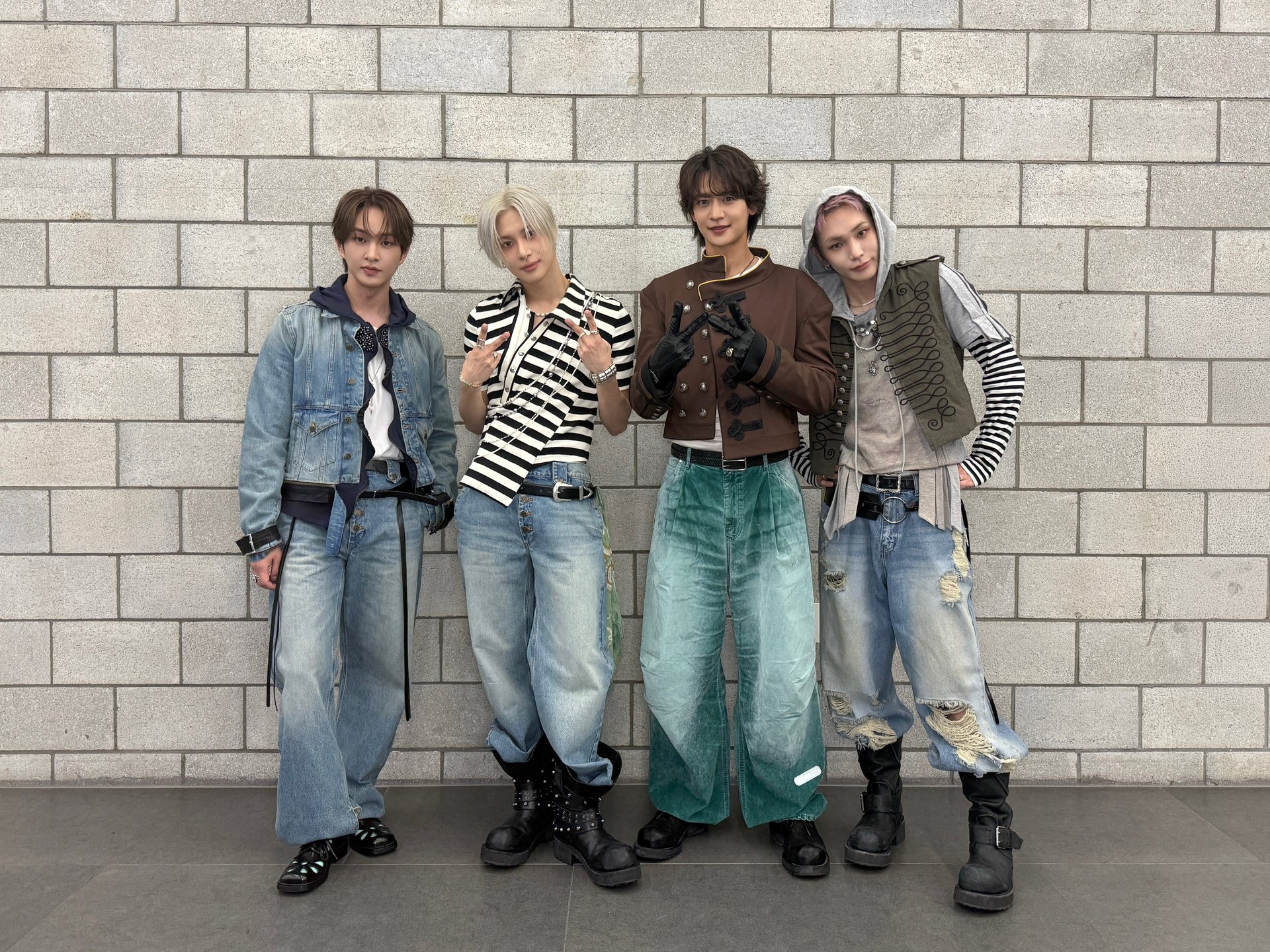 Membrii SHINee stau împreună lângă un perete la locul de filmare al unei emisiuni muzicale
