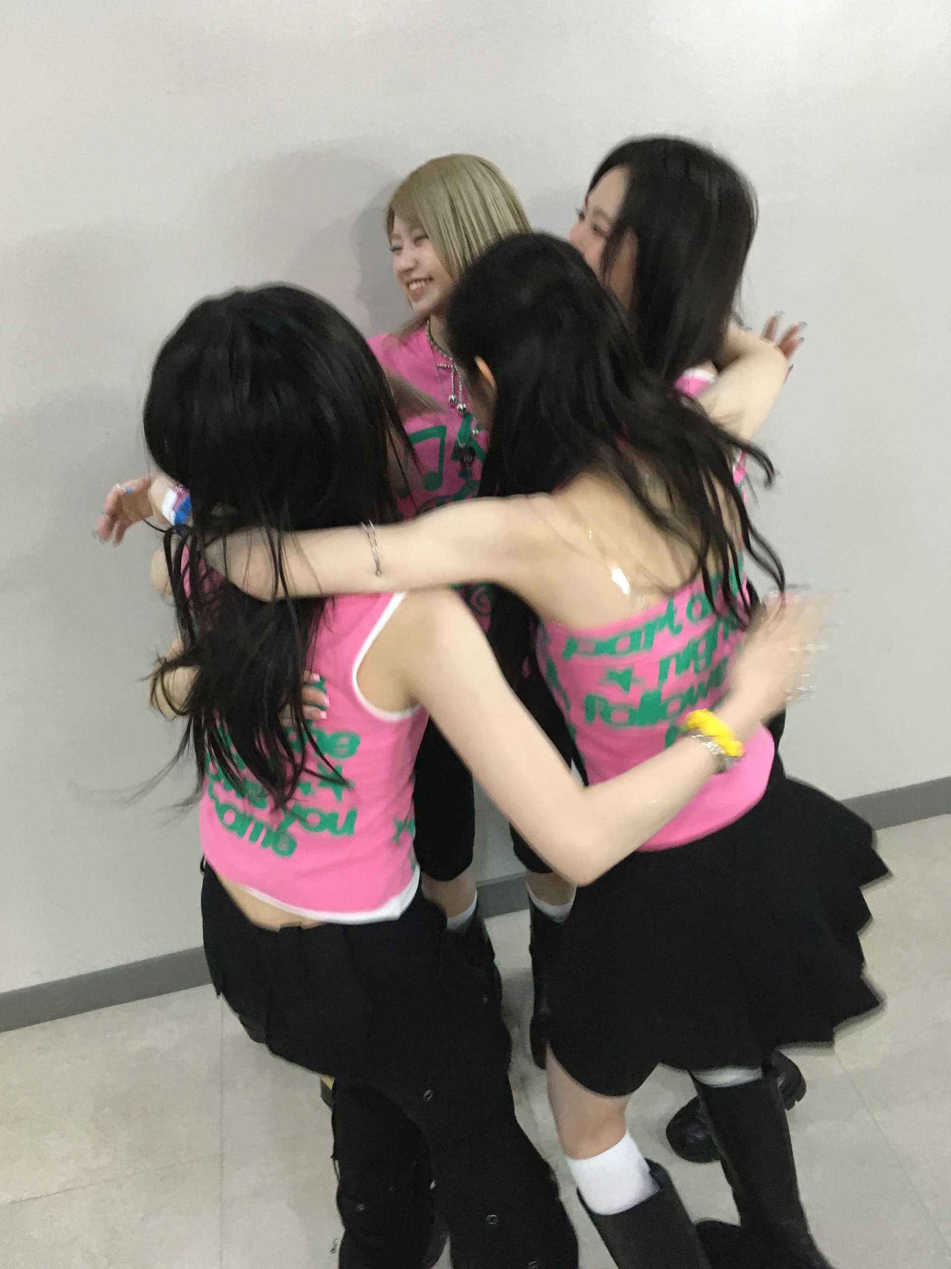 KiiiKiii members embracing in the stage outfits from their first fan concert