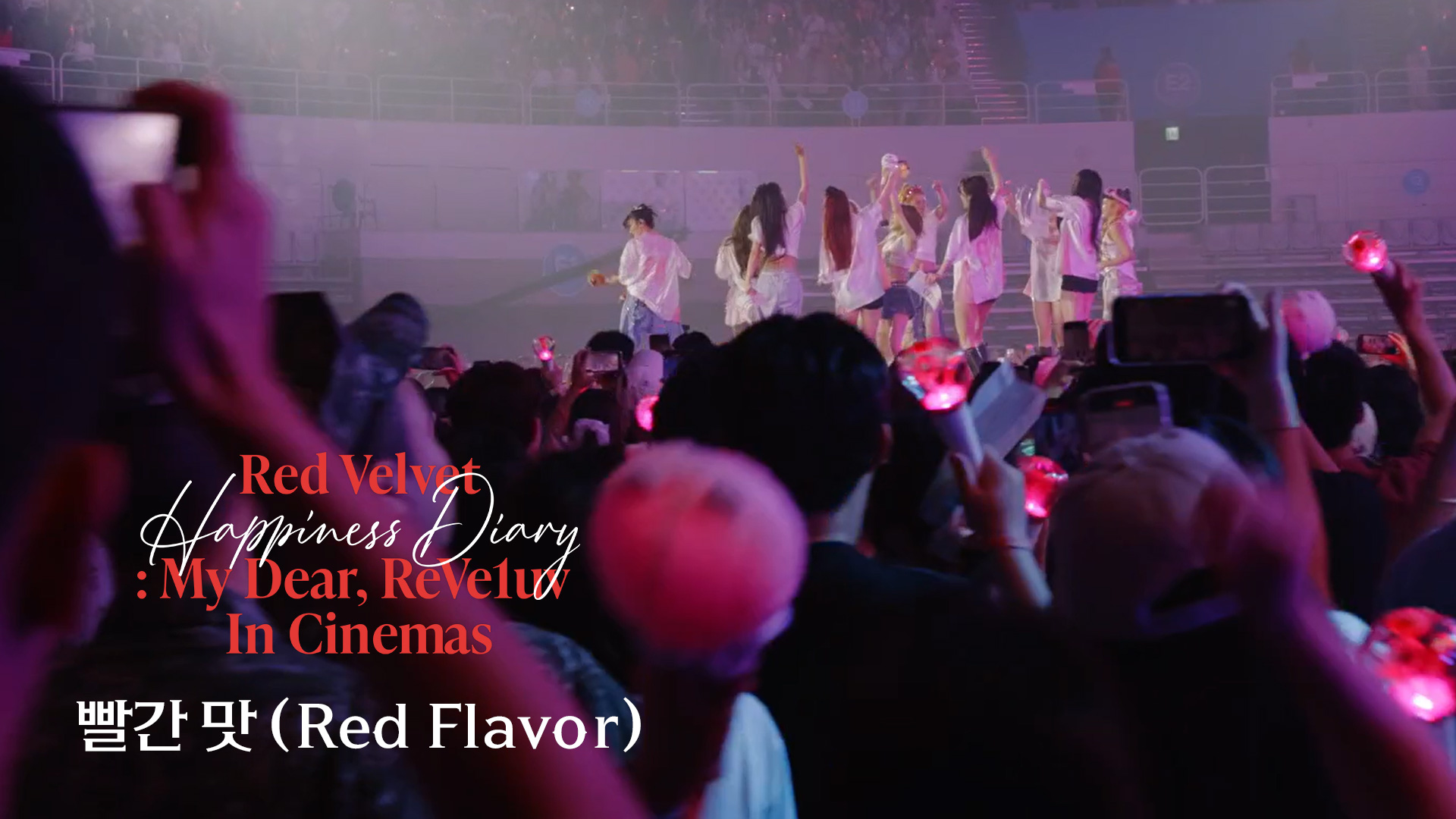 A concert wide shot showing Red Velvet on stage and an audience filled with lightsticks