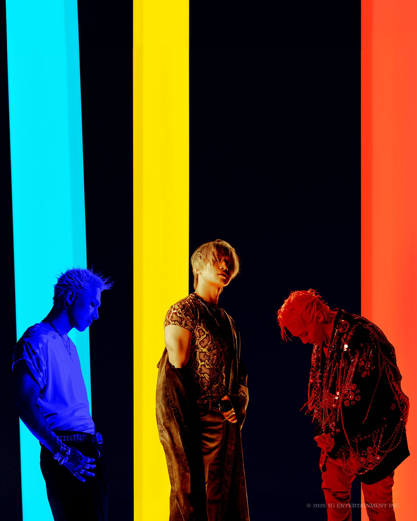 BIGBANG members G-DRAGON, TAEYANG and DAESUNG standing side by side against a color-block backdrop