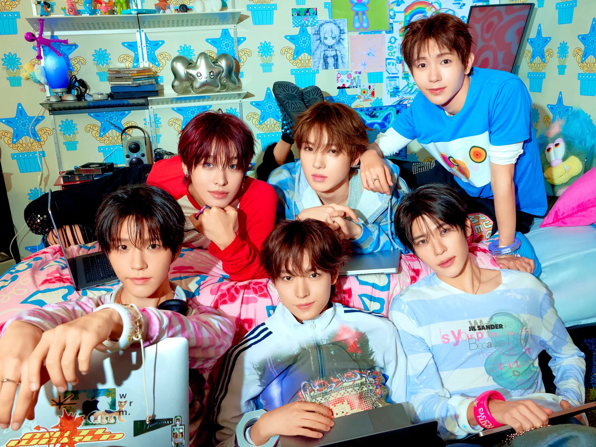 Участники NCT WISH SION, RIKU, YUSHI, JAEHEE, RYO и SAKUYA собрались в комнате, полной ярких цветных реквизитов, и смотрят в камеру — концепт-фото I SPY Lover Boy